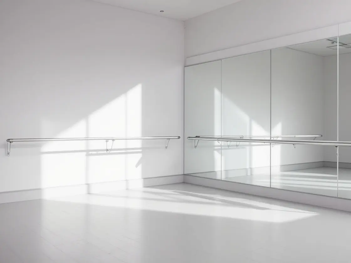 An empty dance studio corner with a barre and a large mirror