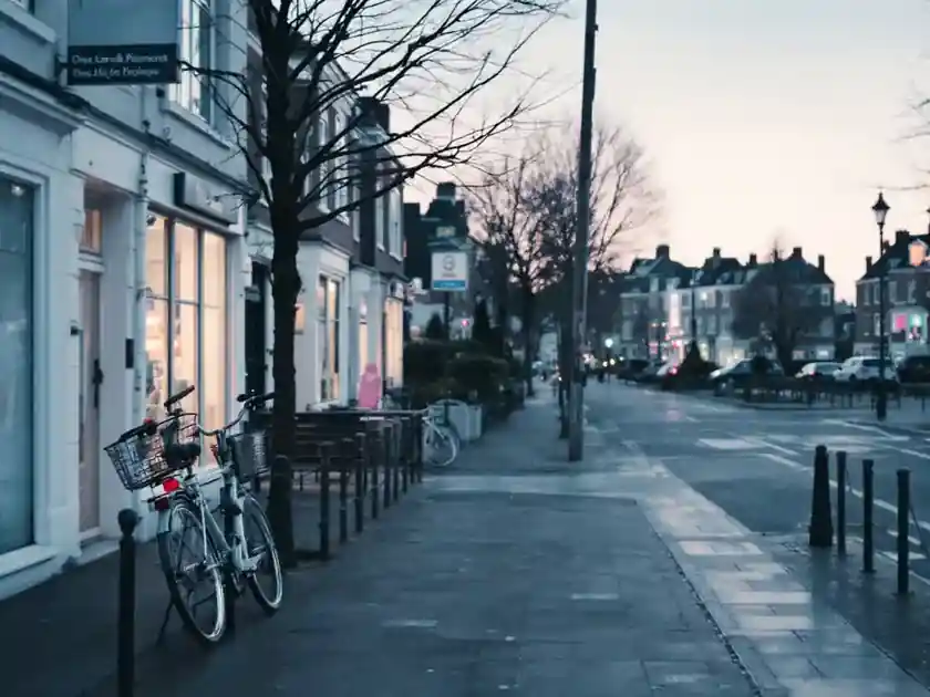 A quiet residential street at dawn with parked bicycles and wet pavement