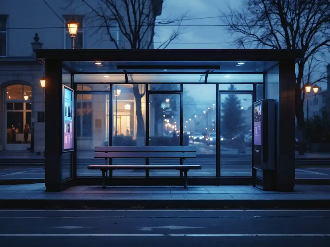 An empty tram stop bench in early evening under a street lamp